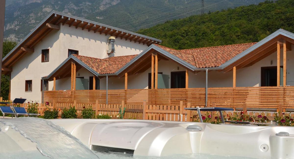 Casa in montagna con tetto in legno, vasca idromassaggio e giardino fiorito.