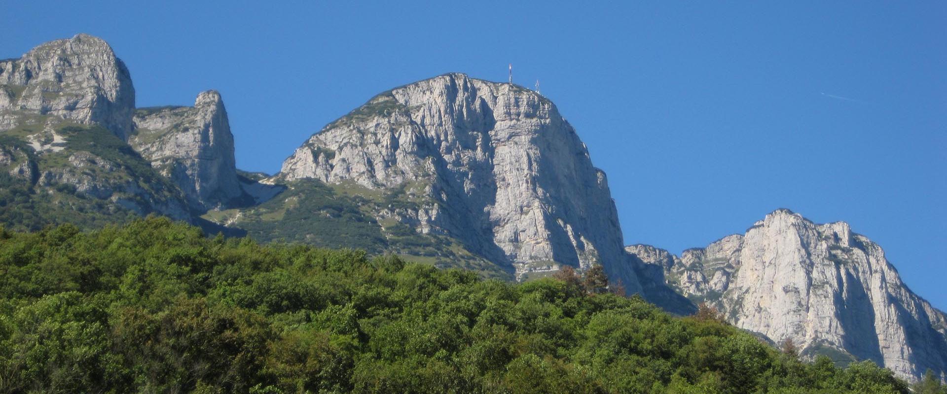 Montagne rocciose con vegetazione verde sotto un cielo limpido e azzurro.