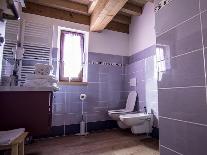 Bagno moderno con piastrelle viola, finestra, asciugamani e travi in legno.