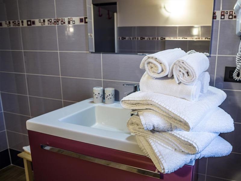 Bagno moderno con asciugamani bianchi, lavabo e asciugacapelli a parete.