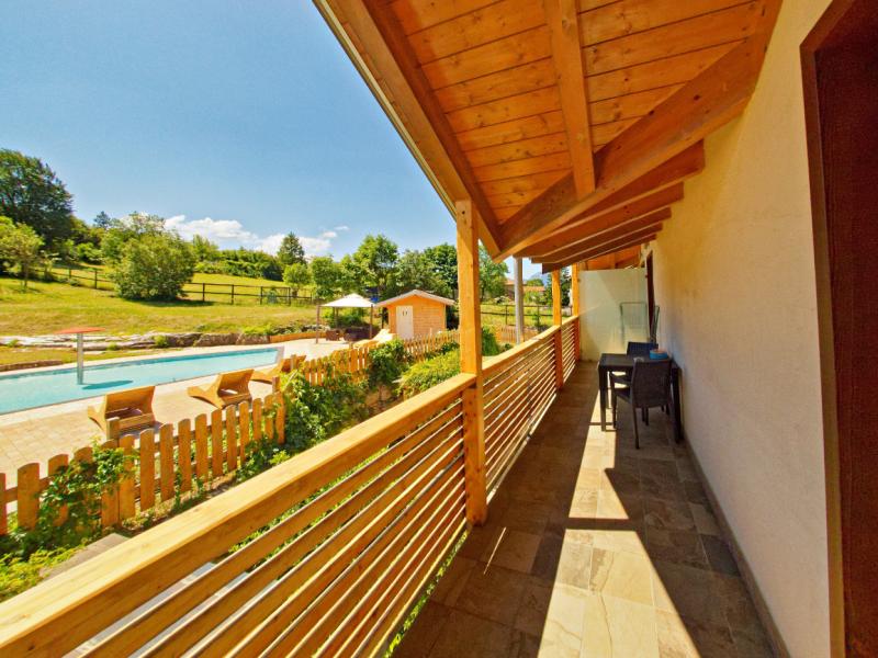 Terrazza con vista piscina e giardino, sotto un tetto in legno.