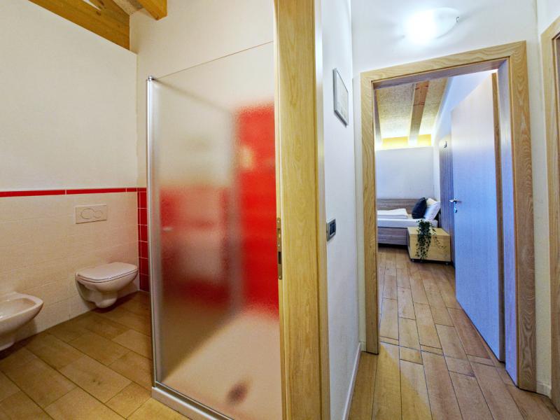 Corridoio con bagno e camera da letto, pavimento in legno, porte in legno chiaro.