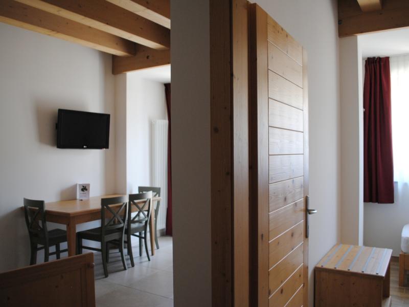 Interno accogliente con tavolo, sedie, TV e dettagli in legno.