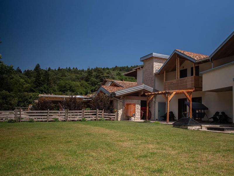 Casa moderna con giardino, tetto spiovente e balcone in legno, immersa nel verde.