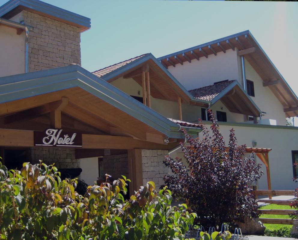 Hotel in stile rustico con tetto in legno e giardino verde.